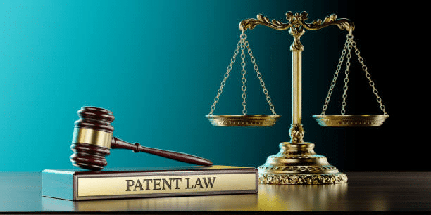 Patent law book with a judge’s gavel and brass scales of justice on a desk, representing intellectual property law and patent protection
