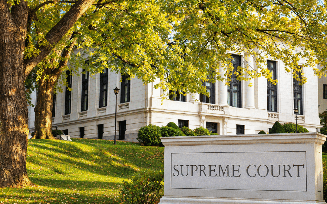 U.S. Supreme Court building and engraved Supreme Court sign surrounded by trees and a landscaped lawn